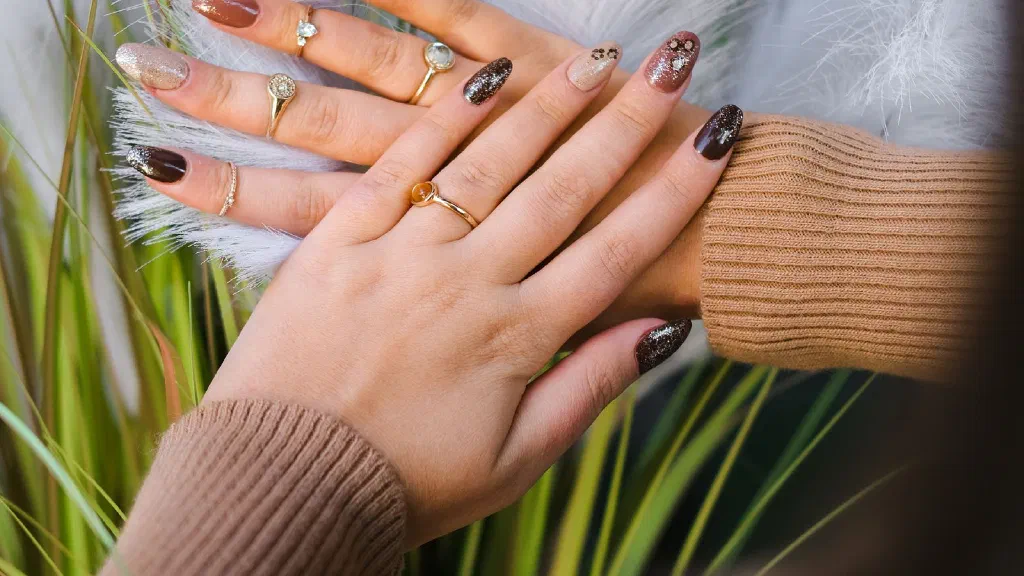 Hand trägt roten Nagellack mit dünner Schicht auf gepflegte Nägel auf